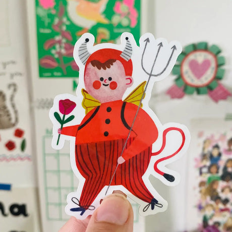 Introducing the LITTLE DEVIL sticker from Daria Solak Illustrations, a whimsical piece to add a touch of fun to your everyday items. Sized at 8 cm, it's the perfect addition to laptops, notebooks, or any surface needing a splash of personality. Each sticker is a print of a hand-drawn illustration, brimming with color and charm. Brighten your day and bring a smile to your face with this playful design.