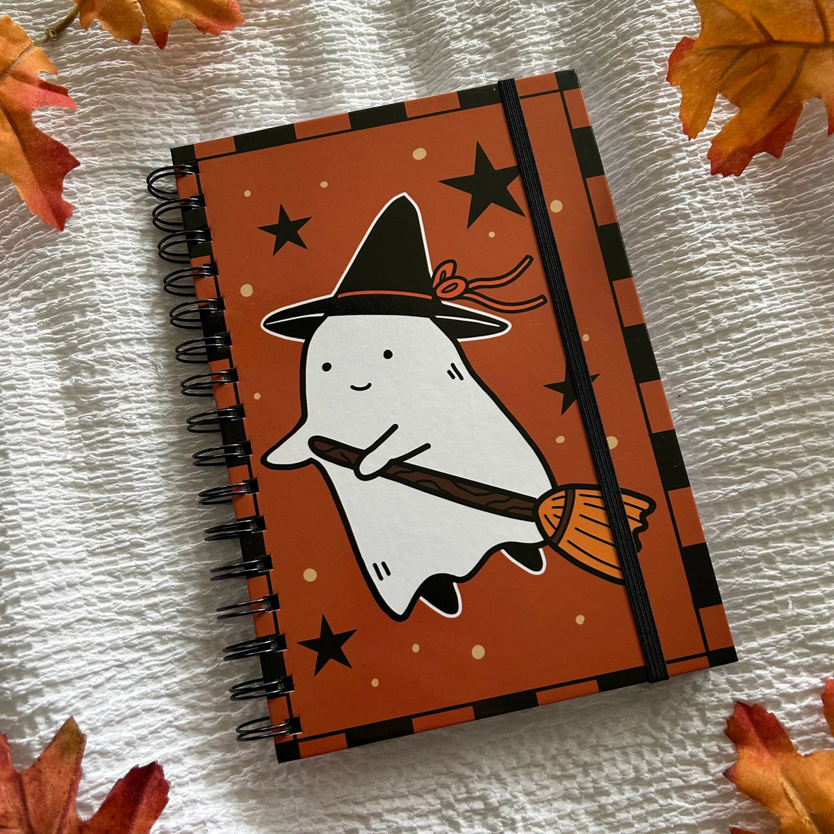 A new A5 notebook featuring a ghost dressing up as a witch!

This hardcover notebook comes lined and with an elastic band. There are 96 double sided pages.