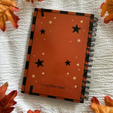 A new A5 notebook featuring a ghost dressing up as a witch!

This hardcover notebook comes lined and with an elastic band. There are 96 double sided pages.