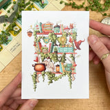 Postcard featuring my original watercolor and ink illustration of the various magical creatures, tiny fairies, and enchanted items nestled on the shelves of a fairy witch, including a magical swan who loves to make potions, a plethora of mushrooms, and a tiny acorn fairy house.