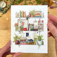 Postcard featuring my original watercolor and ink illustration of the vintage oddities and books tucked away in the shelves of a vintage nurse, including a quintessential nurse’s hat, assortment of plants, and a stethoscope.