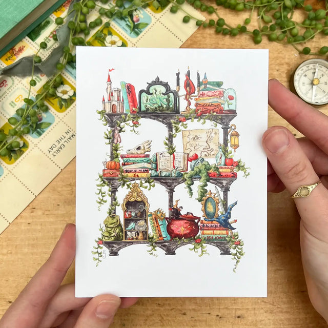 Postcard featuring my original watercolor and ink illustration of the various enchanted items collected by a storybook witch as she travels throughout all your favorite fairytales, including a charming castle, a glass-encased rose, and a brightly colored dragon, all nestled on stone shelves that evoke mysterious castle corridors covered in rose vines.