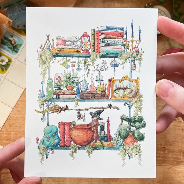 Postcard featuring my original watercolor and ink illustration of the oddities, books, tools, and trinkets tucked away in the shelves of a swamp witch, including an assortment of creatures brewing up a potion, and an alligator skull holding a crystal ball.