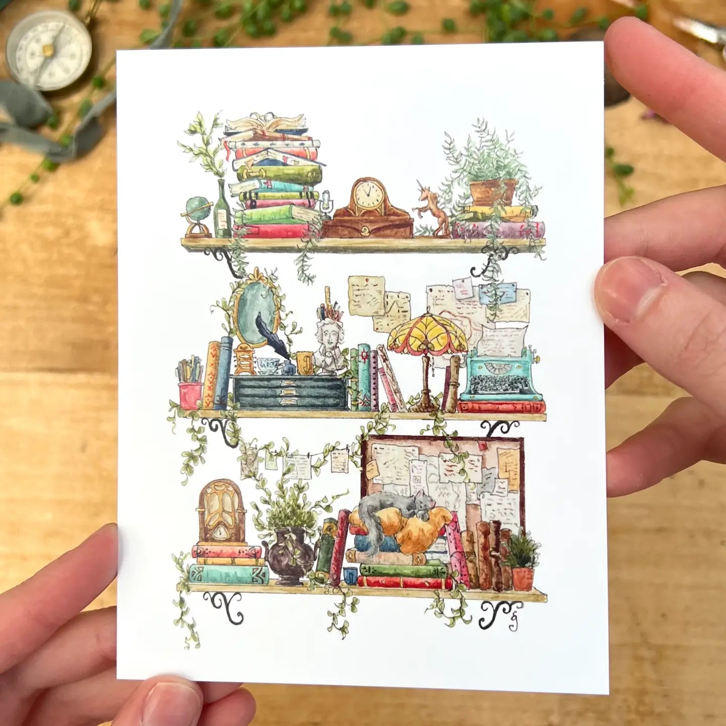 Postcard featuring my original watercolor and ink illustration of the vintage oddities and books tucked away in the shelves of a vintage writer, including a Poe pencil holder, a stained glass lamp, and a blue typewriter.