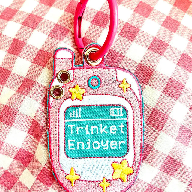 These cute embroidered keychains attach with a colorful ring clasp and are perfect for attaching to your keys or bag to bring with you on all of your adventures! This design features extra grommets to hang more keychains and knick knacks!

Includes one keychain only.
Embroidered on both sides. The design is the same on both sides.
Materials: Cotton, Polyester, Brass