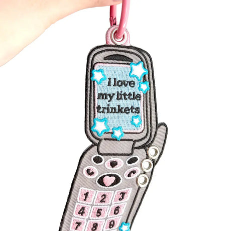 These cute embroidered keychains attach with a colorful ring clasp and are perfect for attaching to your keys or bag to bring with you on all of your adventures!

This particular cell phone design is inspired by Y2K and 2000s. It features extra silver grommets to hang more keychains and showcase your favorite charms! Perfect for any trinket and knick knack hoarder.

Includes one keychain only.
Embroidered on both sides.&nbsp;
Materials: Cotton, Polyester, Brass