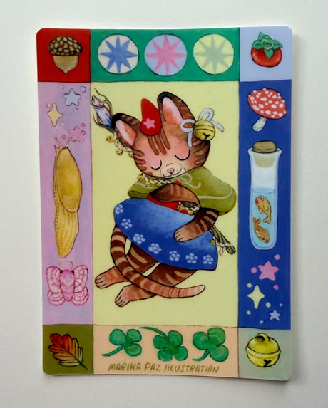 Folk art and magical elements frame a magical cat on this vinyl sticker.

This vinyl matte sticker is weather and waterproof-stick it on a notebook, bike, or car- it's going to stick around! Heck, throw it on a water bottle and through the dishwasher. This sticker can go anywhere. Sticker measures 4.5" x 3.25" Printed in USA.