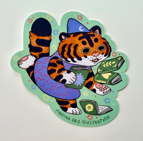 This tiger loves books so much, she can't hold them all at once!

This vinyl matte sticker is weather and waterproof-stick it on a notebook, bike, or car- it's going to stick around! Heck, throw it on a water bottle and through the dishwasher. This sticker can go anywhere. Sticker measures 4" x 4" Printed in USA.