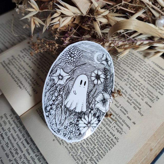 A little ghostie in a flower meadow, printed on a sticker to add some wholesome spooky charm to your laptop, water bottle, or any other surface. From my original pen and ink artwork.

Die-cut vinyl sticker, suitable for interior or exterior use. Measures approximately 76mm (3 inches) tall.