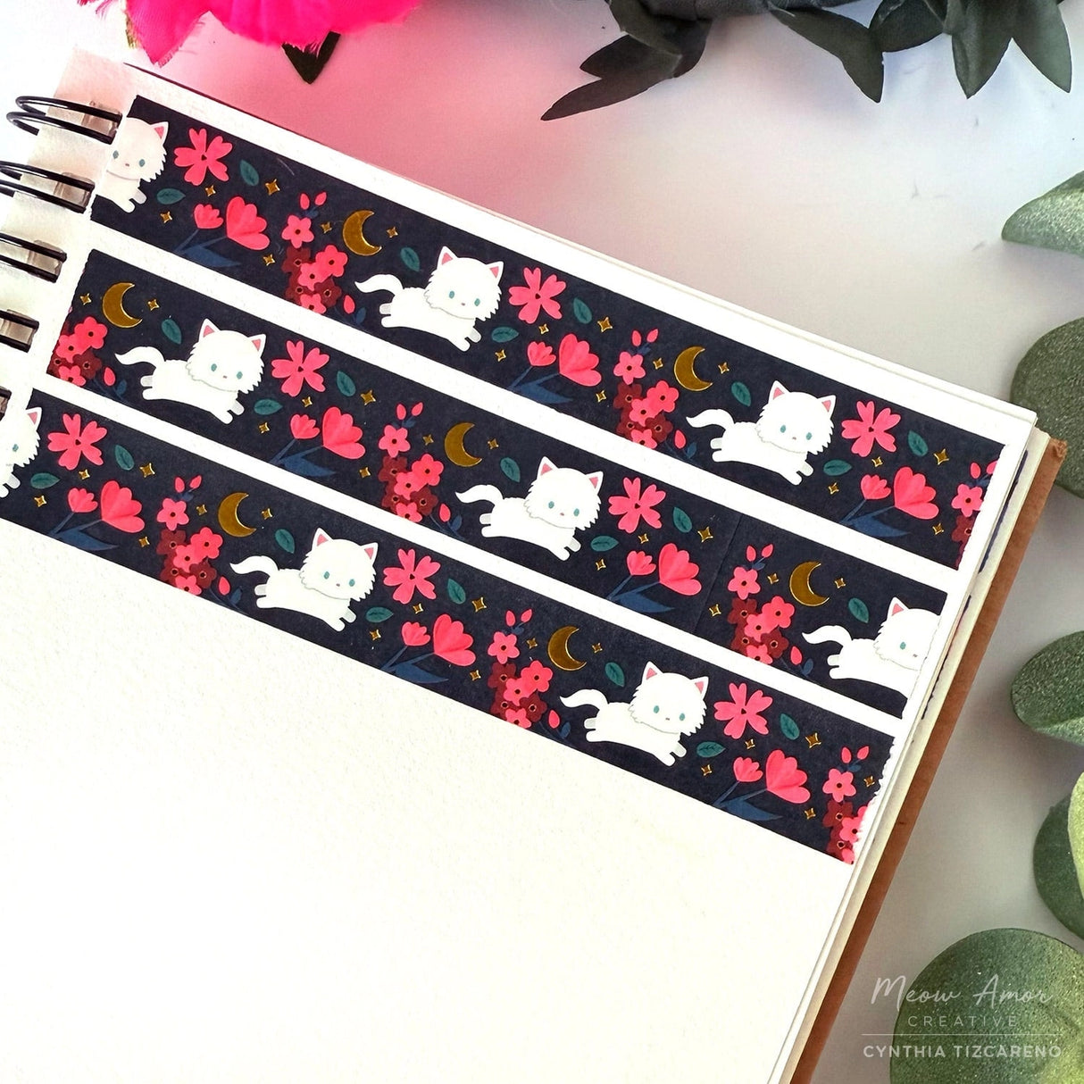 Brighten your crafts with the Floral Fluffy White Cat Gold Foil Washi Tape. Featuring a fluffy white cat surrounded by delicate pink florals set against a sleek black background, this tape is enhanced with shimmering gold foil details for a charming and elegant look. Perfect for adding a sweet, stylish touch to your planners, gifts, and creative projects.

Gold Foil Details&nbsp;
One 10-meter long roll of washi tape
15mm wide
32mm paper core