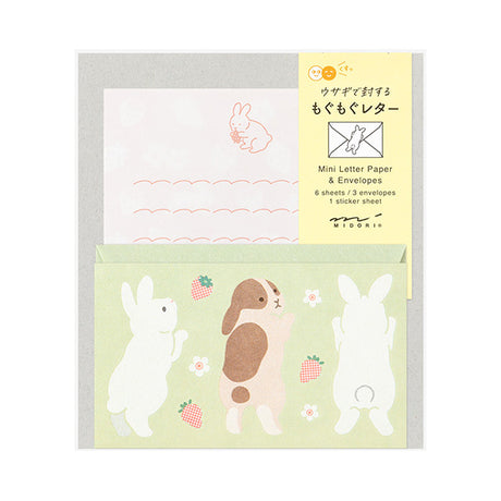 The set shows a rabbit stretching and chasing a strawberry. The stationery paper is a soft pink color inspired by strawberries. The ruled lines are designed to evoke the image of a rabbit bouncing around.