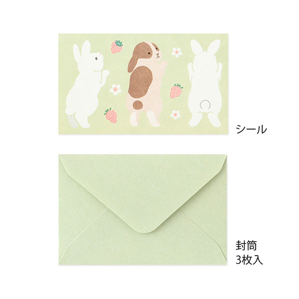 The set shows a rabbit stretching and chasing a strawberry. The stationery paper is a soft pink color inspired by strawberries. The ruled lines are designed to evoke the image of a rabbit bouncing around.