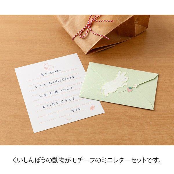 The set shows a rabbit stretching and chasing a strawberry. The stationery paper is a soft pink color inspired by strawberries. The ruled lines are designed to evoke the image of a rabbit bouncing around.