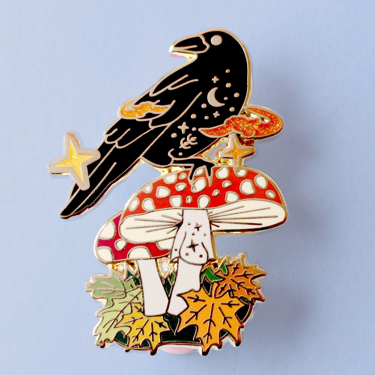 This enamel pin features Crow sitting a fall mushroom, surrounded by mystical orange smoke. The pin is presented on a Glitter Punk backing card and is secured with 2 pin backs.

This pin is part of the Corvid Collection, an 8-part series of bird pins. 

Measurements: 46mm