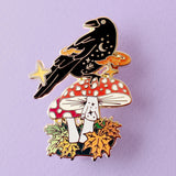 This enamel pin features Crow sitting a fall mushroom, surrounded by mystical orange smoke. The pin is presented on a Glitter Punk backing card and is secured with 2 pin backs.

This pin is part of the Corvid Collection, an 8-part series of bird pins. 

Measurements: 46mm