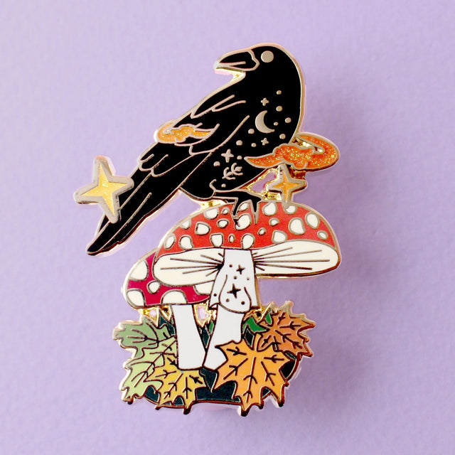 This enamel pin features Crow sitting a fall mushroom, surrounded by mystical orange smoke. The pin is presented on a Glitter Punk backing card and is secured with 2 pin backs.

This pin is part of the Corvid Collection, an 8-part series of bird pins. 

Measurements: 46mm
