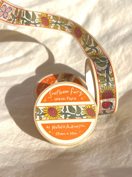 This washi tape features little sunflowers dancing one by one separated by flowers and strawberries. This tape design is taken from my Sunflower Fairy print's decorative borders.

This roll is 15mm wide x 10m of paper tape. Washi tape is super durable and flexible. It tears easily and can be safely applied to a variety of surfaces; it doesn’t leave a sticky residue behind, making it especially ideal for stationery and hanging prints temporarily.