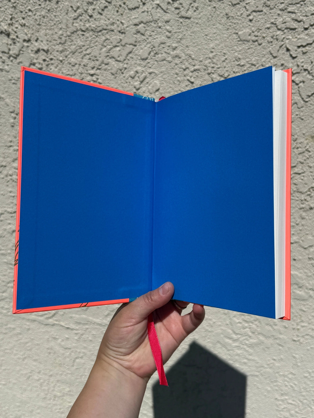 This is a blank 200 page notebook/sketchbook with thin ivory Munken paper perfect for light sketching or writing. Part of a fantasy collection called Woodfolk.

The cover is fluorescent pink/orange and has a smooth matte finish with gold foiling on the front and back. Plus it has a blue fabric spine with white embossing, adding to the charm of the book. Best for pencils, light pens, and generally light mediums, as thick markers or water can bleed. Not recommended for gouache or heavy marker use.