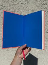 This is a blank 200 page notebook/sketchbook with thin ivory Munken paper perfect for light sketching or writing. Part of a fantasy collection called Woodfolk.

The cover is fluorescent pink/orange and has a smooth matte finish with gold foiling on the front and back. Plus it has a blue fabric spine with white embossing, adding to the charm of the book. Best for pencils, light pens, and generally light mediums, as thick markers or water can bleed. Not recommended for gouache or heavy marker use.