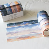 This washi tape box set is designed for journalers, sky gazers, and stationery lovers who find beauty in the ever-changing colours of the sky. Featuring four digitally drawn skyscape designs by Rebecca, each roll captures a different season, from soft spring sunrises to moody winter twilights, all packaged in a beautiful presentation box.

The four designs included:

&nbsp;* Cloudy Days Spring — soft purple and peach sunrise tones&nbsp;
&nbsp;* Cloudy Days Summer — sky blue with drifting white clouds&nbsp;
