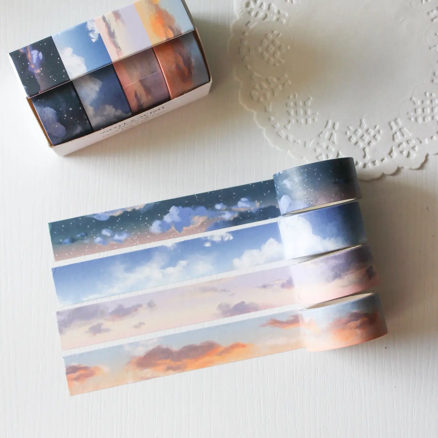 This washi tape box set is designed for journalers, sky gazers, and stationery lovers who find beauty in the ever-changing colours of the sky. Featuring four digitally drawn skyscape designs by Rebecca, each roll captures a different season, from soft spring sunrises to moody winter twilights, all packaged in a beautiful presentation box.

The four designs included:

&nbsp;* Cloudy Days Spring — soft purple and peach sunrise tones&nbsp;
&nbsp;* Cloudy Days Summer — sky blue with drifting white clouds&nbsp;
