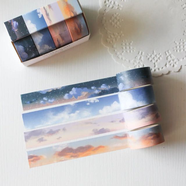 This washi tape box set is designed for journalers, sky gazers, and stationery lovers who find beauty in the ever-changing colours of the sky. Featuring four digitally drawn skyscape designs by Rebecca, each roll captures a different season, from soft spring sunrises to moody winter twilights, all packaged in a beautiful presentation box.

The four designs included:

&nbsp;* Cloudy Days Spring — soft purple and peach sunrise tones&nbsp;
&nbsp;* Cloudy Days Summer — sky blue with drifting white clouds&nbsp;
