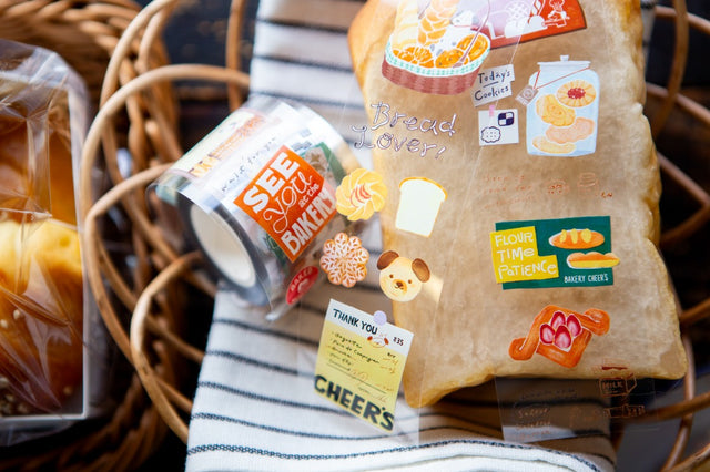 OURS Studio Bakery Cheer’s PET Tape Packaged bread with decorative stickers on a woven basket background