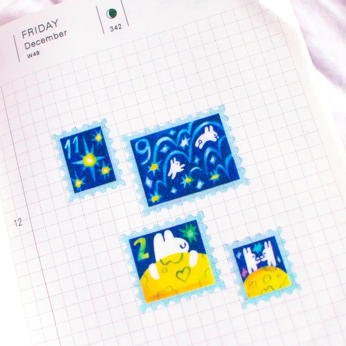 'To the Moon &amp; Back' Frosted Glitter Transparent A6 Sticker Sheet. Stickers are stamp shaped and have a clear blue background.

Not waterproof.
Do not place in areas of high wear (laptops, phone cases, water bottles, etc).
Sticker sheets come packaged in a plastic sleeve.