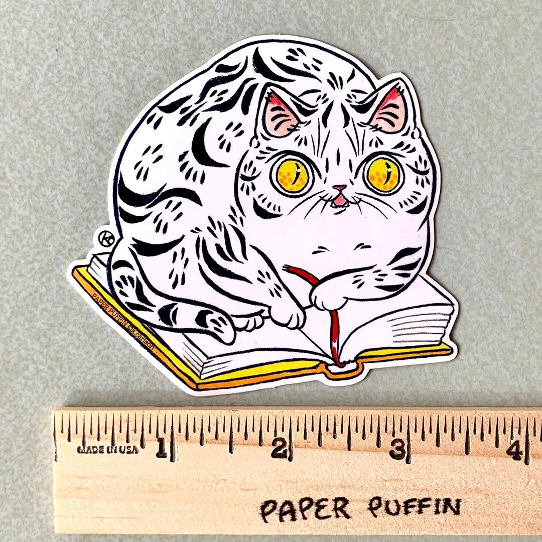 A cat sitting on a favorite book, helping you keep your spot. 

+ size:3.3" x 3.4”
+ permanent adhesive glossy vinyl sticker with solid peel backing
+ scratch and weather resistant material, PVC free
+ packaged and shipped flat

All work and photos ©PAPER PUFFIN Art by. K.CARLSON