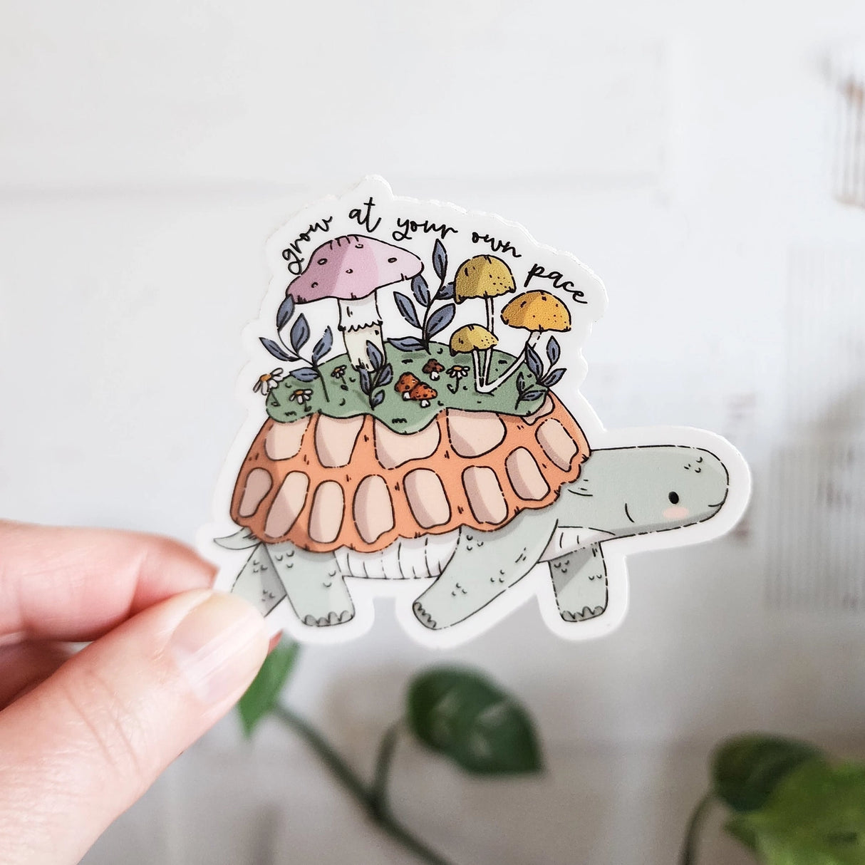 A turtle travels along a mossy path in Wildflower Woods, carrying a tiny mushroom meadow on its back as it moves steadily forward. This vinyl sticker captures that unhurried moment, carrying a gentle reminder that growth happens in its own time.

Made from durable, waterproof vinyl, this sticker is designed to hold up wherever you place it—whether that’s a water bottle, laptop, or journal you reach for daily.