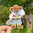 This sticker features my illustration of a raccoon cowhand showing off their rainbow-fringed shirt and matching Pride hat and boots. They’re tipping their hat to show that they respect and admire you for living your truth!

This die-cut gloss vinyl sticker is durable, weatherproof, and perfect for water bottles, notebooks, laptops, bikes, and all sorts of other surfaces! Make sure to clean and dry the surface thoroughly before applying