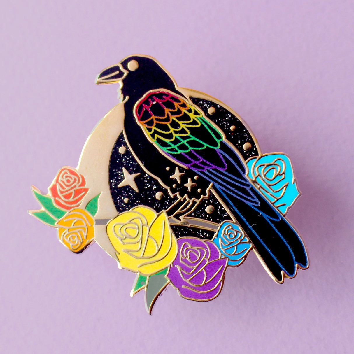 This enamel pin features a black raven with rainbow-coloured wings. It’s sitting on a branch surrounded by rainbow-coloured roses, in front of a glittery moon. The pin is presented on a Glitter Punk backing card and is secured with 2 pin backs.

This pin is part of the Corvid Collection, an 8-part series of bird pins. 

Measurements: 42mm