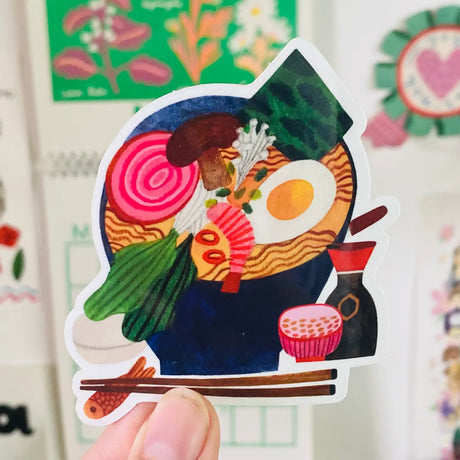 Add a playful touch to your belongings with the Ramen Set sticker from Daria Solak Illustrations. This London-based illustrator creates vibrant designs that are sure to make you smile. Sized at 8 cm, it's the perfect way to express your love for this popular dish. Each sticker originates from a hand-drawn illustration and is printed locally, making it a unique piece of art. Enjoy the colorful, food-themed creations of Daria Solak and let your personal items reflect your fun-loving personality.