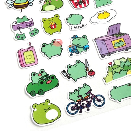 This is part of a new series of sticker sheets that feature different "days".

There are 25 individual stickers on the sheet full of FROGS.

They are vinyl stickers on a clear plastic sheet with a backing card. The bag has a hanging hole for retail display.

The whole packaging is 3.8 x 8.75" and is ready to hang.
The sticker sheet is 3.75 x 5.8"
