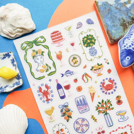 🍋🦞 Ciao to sunny days, seaside snacks, and a table full of color! This playful sheet is packed with lemons, tomatoes, seafood, spritzes, sardines, patterned tiles, and plenty of Mediterranean flair. Add in a few artsy portraits and bright floral details, and it’s basically a whole summer getaway squeezed onto one sticker sheet.

Top Coating: None
Adhesive Layer: PVC (plastic)
Backing Layer: Clear
6.69" x 3.54".
Weight - 0.03lbs
1 sheet included