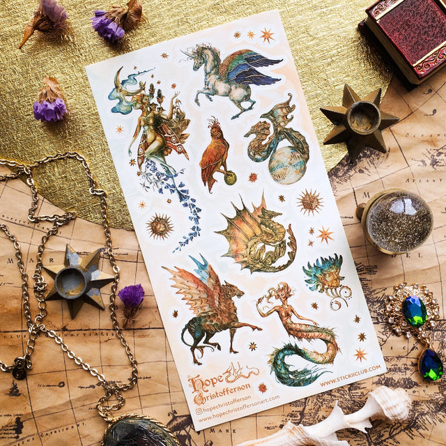 🦄🐉 Soaring through starlit skies and shimmering seas, @hopechristofferson’s mythical beings awaken a realm of untamed magic and ancient wonder. From a winged alicorn and celestial dragons to radiant sirens and cosmic creatures, get ready to weave epic fantasy tales and fill your pages with legendary beauty with this breathtaking sheet.

Art by: @hopechristofferson

Top Coating: Gold Foil
Adhesive Layer: Paper
Backing Layer: Paper
6.69" x 3.54".
Weight - 0.03lbs.
1 sheet included 