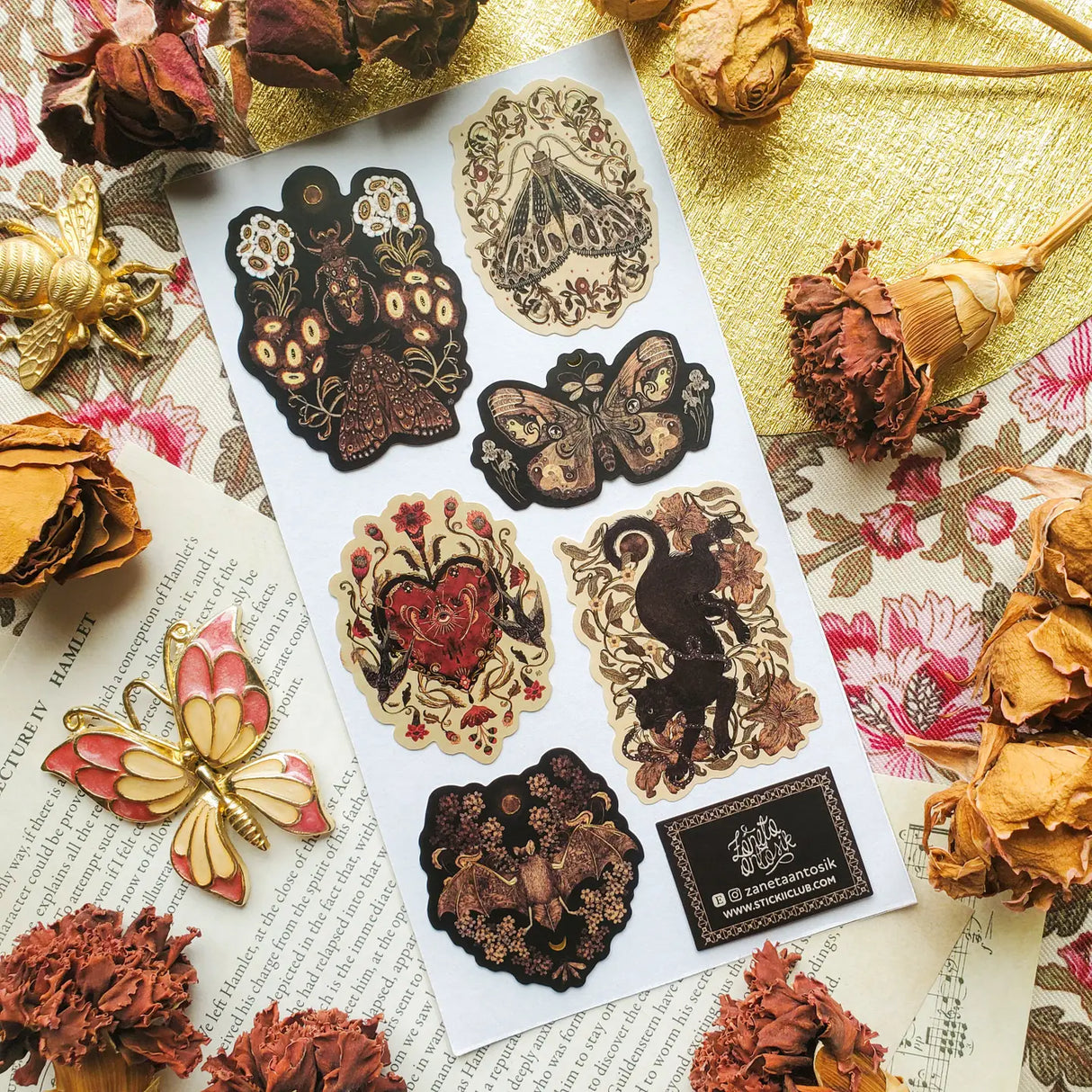 🌙🪲 In this twilight garden by @zanetaantosik, moths, beetles, and shadowy creatures bloom among ornate florals and eclipsed moons. A black cat prowls through curling vines, velvet wings unfurl, and a bat drifts silently across shadowed blossoms — each creature a guardian of this enchanted realm. Perfect for those who find wonder in the dark and poetry in the wild. Art by: @zanetaantosik

Top Coating: Gold Foil
Adhesive Layer: Paper
Backing Layer: Paper
6.69" x 3.54".
Weight - 0.03lbs.
1 sheet included &nb