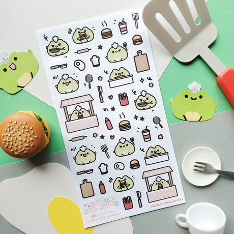 🍔🐸 Say hello to the cutest chef in town! @keziacreations’ adorable little froggy is busy in the kitchen flipping patties and serving up smiles. From sizzling burgers to crispy fries and fizzy drinks, this tiny chef is here to make your heart (and tummy) hoppy.

Art by: @keziacreations

Top Coating: None
Adhesive Layer: Paper
Backing Layer: Clear PET
6.69" x 3.54".
Weight - 0.03lbs.
1 sheet included&nbsp;