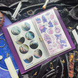 A little moonlit magic for your sticker collection! 🪄 With its celestial vibe and charming feline familiar, our brand new binder will keep your sticker sheets safely tucked away and beautifully organized. Perfect for cozy journaling nights, planning under the moonlight, and growing your sticker stash in style. ✨

Each organizer features a vegan leather cover with a shimmering gold foil emblem and holds up to 48 sticker sheets across 24 pages.

🌙🐈 Moonlit Cat  – Rich violet with a golden cat gazing out a 