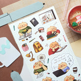 @chaioverdose’s hardworking kitty knows that studying is a full-time adventure! Between tackling tricky equations, filling notebooks with notes, attending online classes, and squeezing in a quick nap on a stack of books, there’s always something to keep those paws busy. Luckily, a little instant ramen and plenty of coffee are here to help this studious cat power through!

Art by: @chaioverdose
One sticker sheet is included.
Top Coating: None
Adhesive Layer: Paper
Backing Layer: Paper
Size: 6.69"x3.54"
