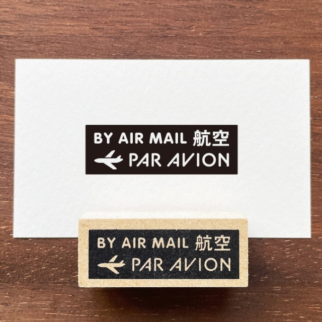 Stamp Marche Air Mail Wooden Stamp Two 'By Air Mail Par Avion' stamps on a wooden surface with a white card.