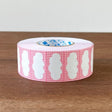 Stamp Marche Label Sticker Roll - Cherry Frame Roll of pink tape with white paw prints on a wooden surface