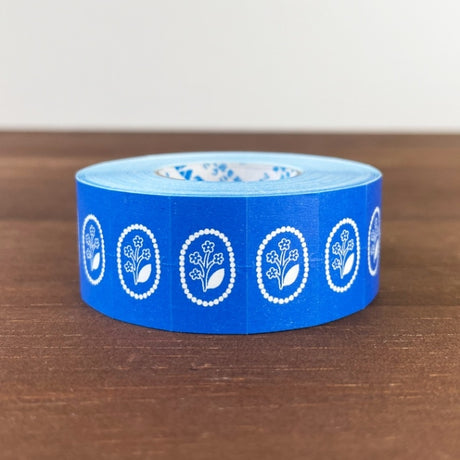 Stamp Marche Label Sticker Roll - Flower Brooch Blue Blue tape with white floral designs on a wooden surface