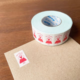 Roll of decorative tape with red designs on a wooden surface