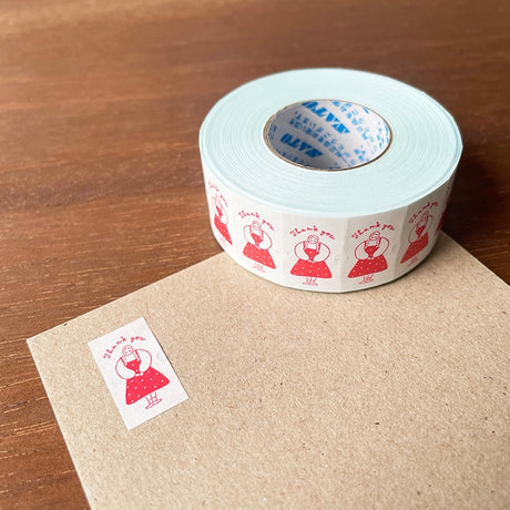 Roll of decorative tape with red designs on a wooden surface