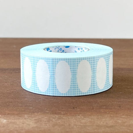 Stamp Marche Label Sticker Roll - Oval Frame Ramune Roll of blue tape with white oval patterns on a wooden surface
