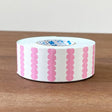 Roll of pink and white patterned tape on a wooden surface