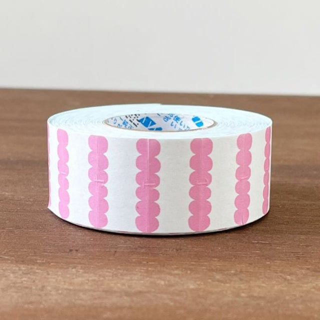 Roll of pink and white patterned tape on a wooden surface
