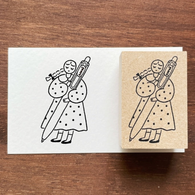 Stamp Marche Maru-Chan Uni-ball Wooden Stamp Rubber stamp with a design of two figures holding a large pen on a wooden surface.