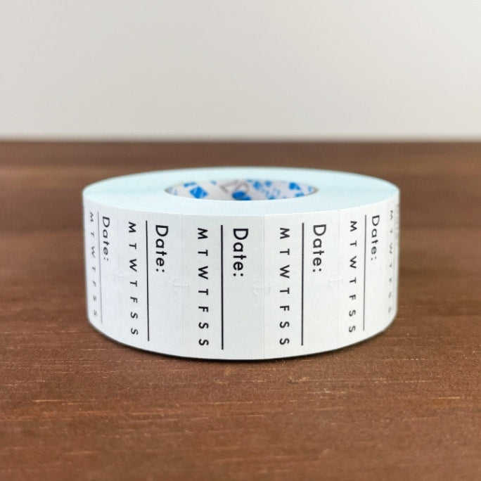 Stamp Marche Planner Label Sticker Roll - Date and Days of the Week Roll of tape with date and day-of-week markings on a wooden surface